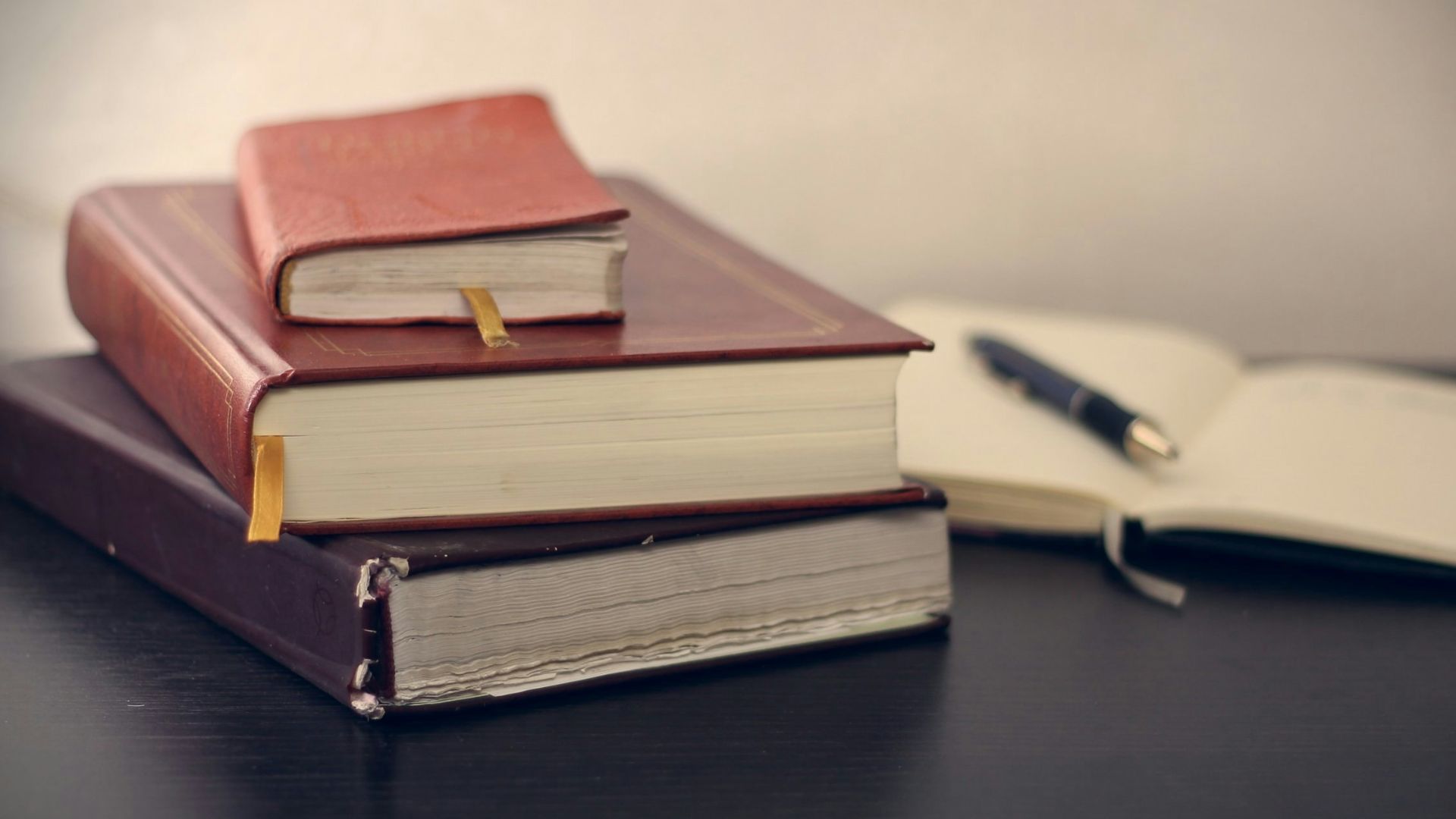 selective focus photography of three books beside opened notebook
