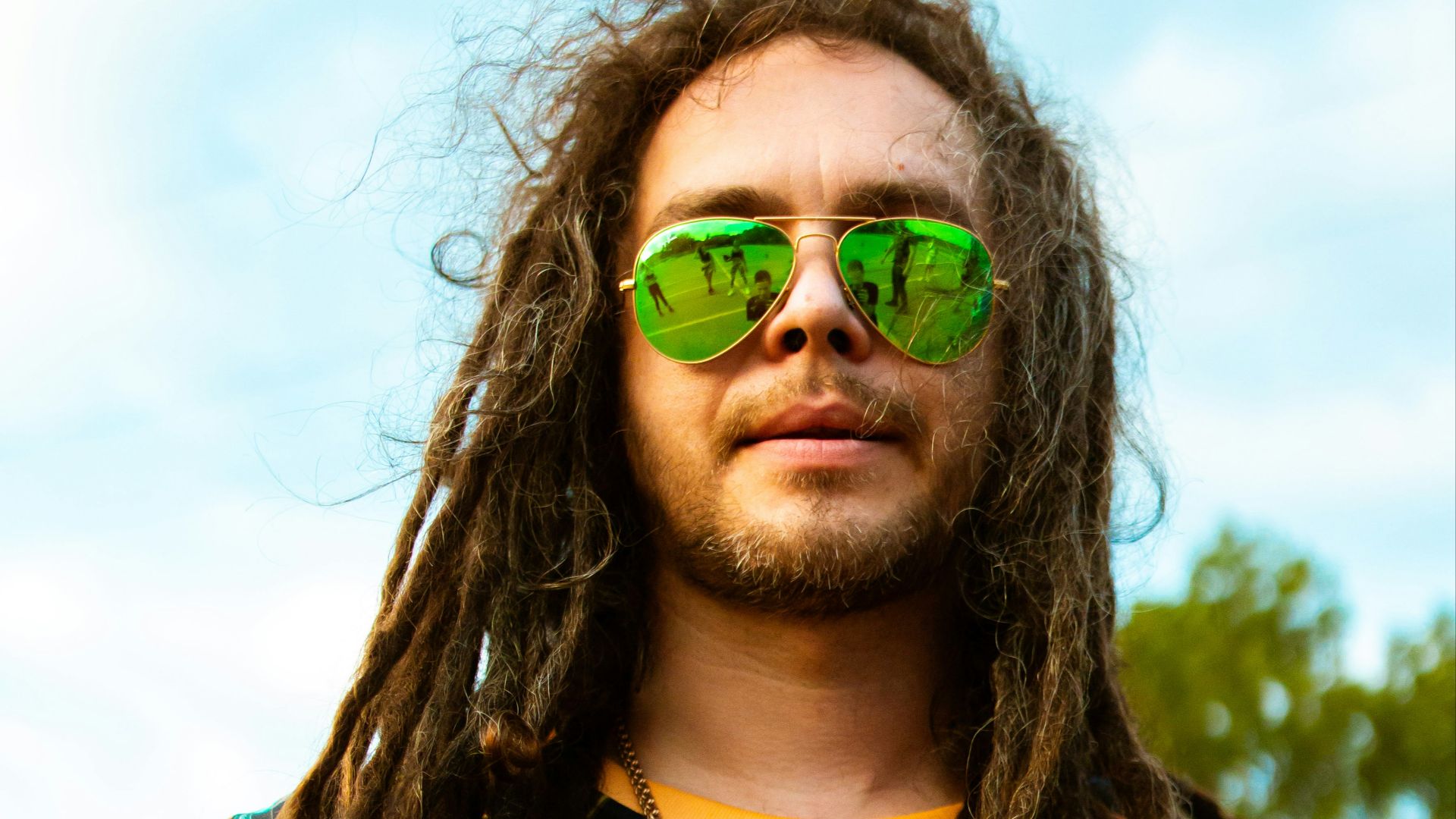 woman in blue yellow and red floral shirt wearing green sunglasses