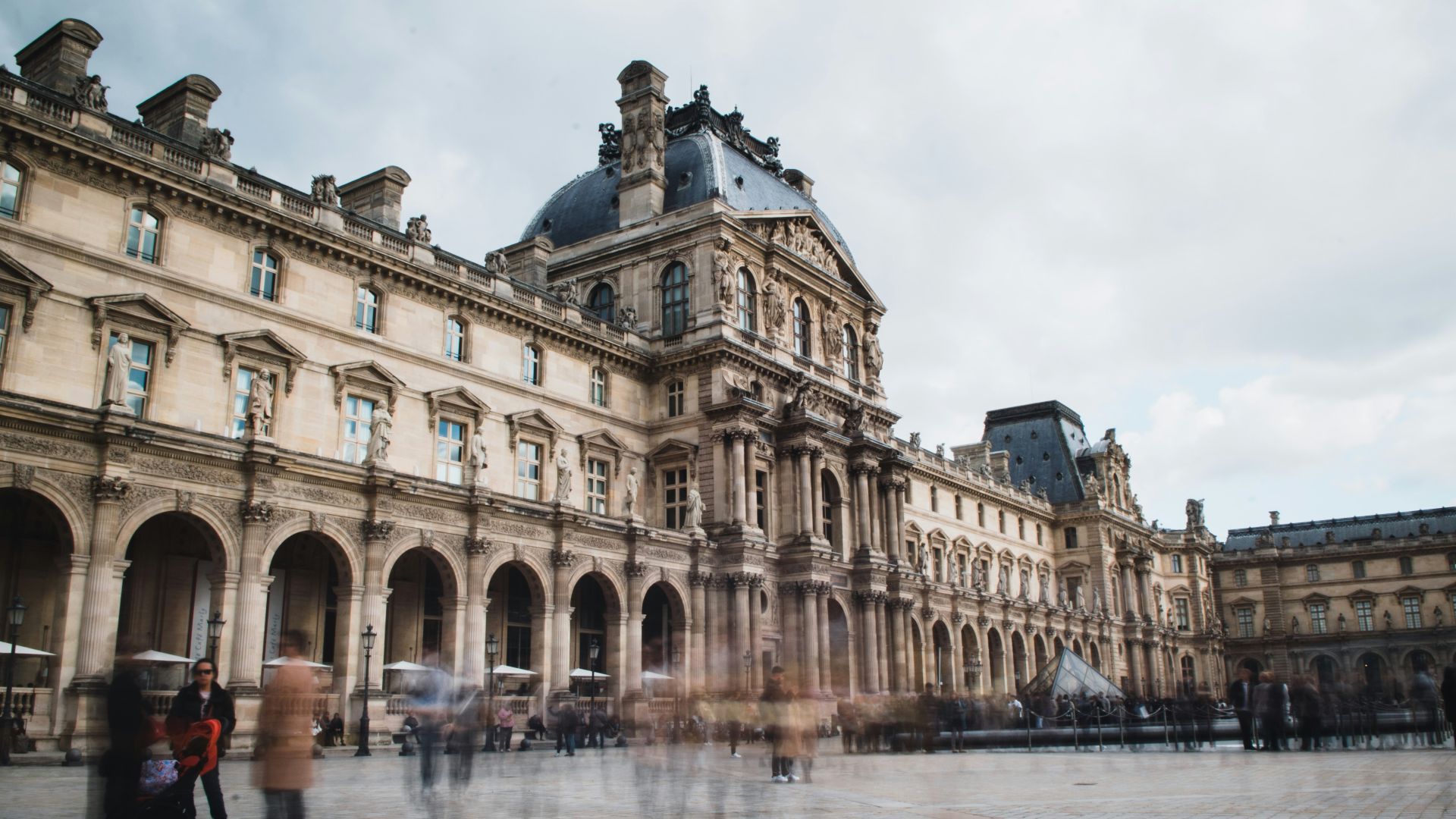 a large building with a courtyard with Louvre in the background