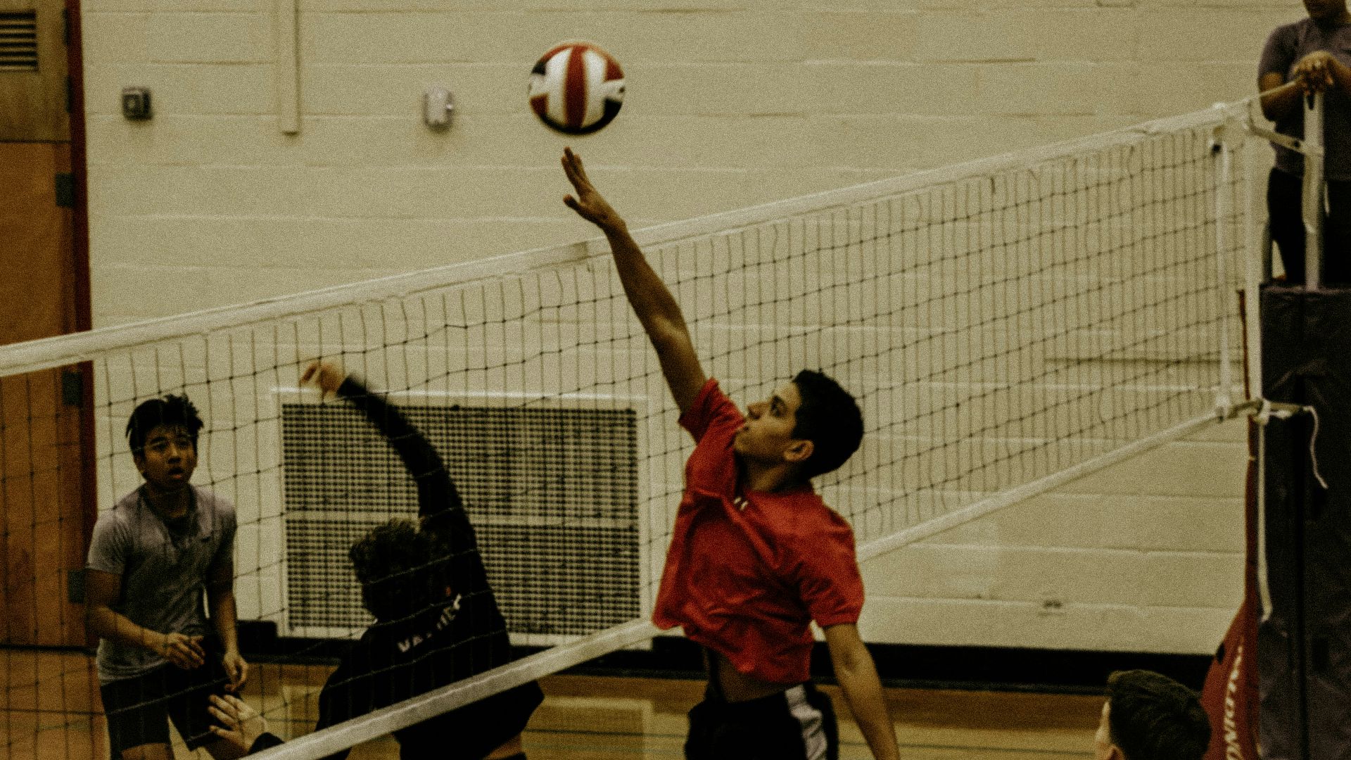 2 boys playing volleyball on court