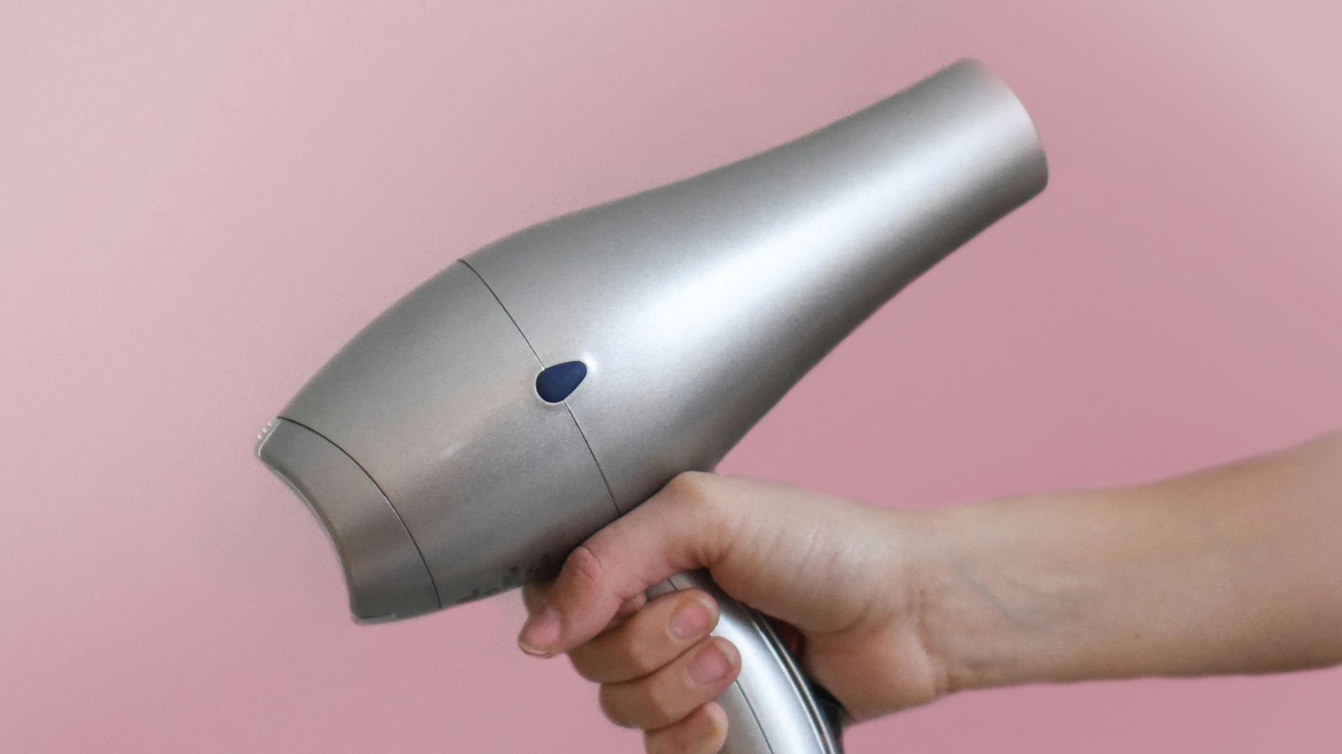 person holding gray corded hair dryer