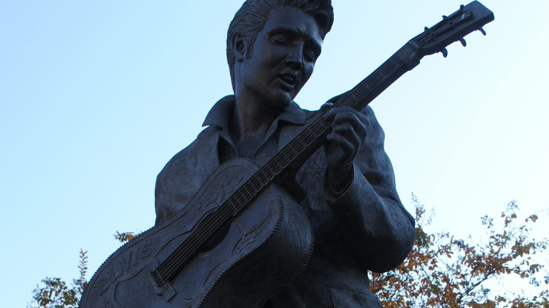 man holding stick statue under white sky during daytime
