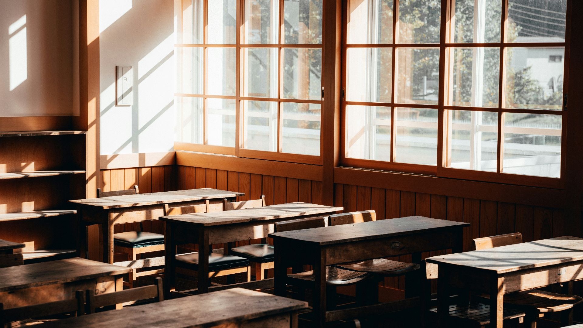 an empty classroom with wooden desks and windows