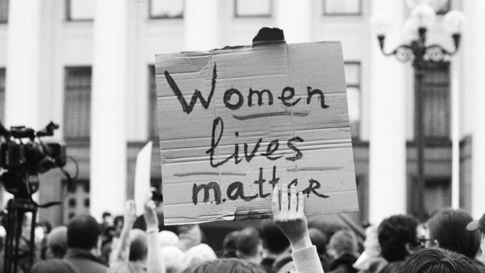 grayscale photo of people holding a white and black printed banner