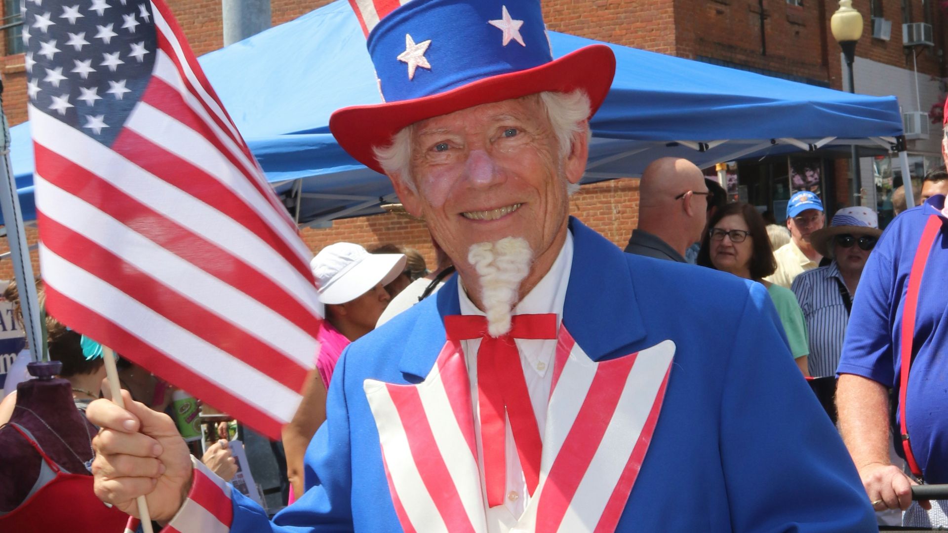 man in blue white and red striped long sleeve shirt standing near people during daytime