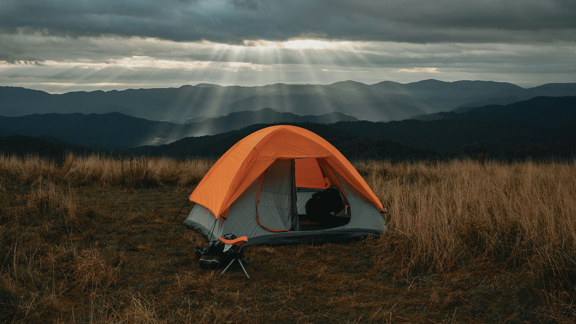 set-up gray and orange tent on brown field under cloudy sky