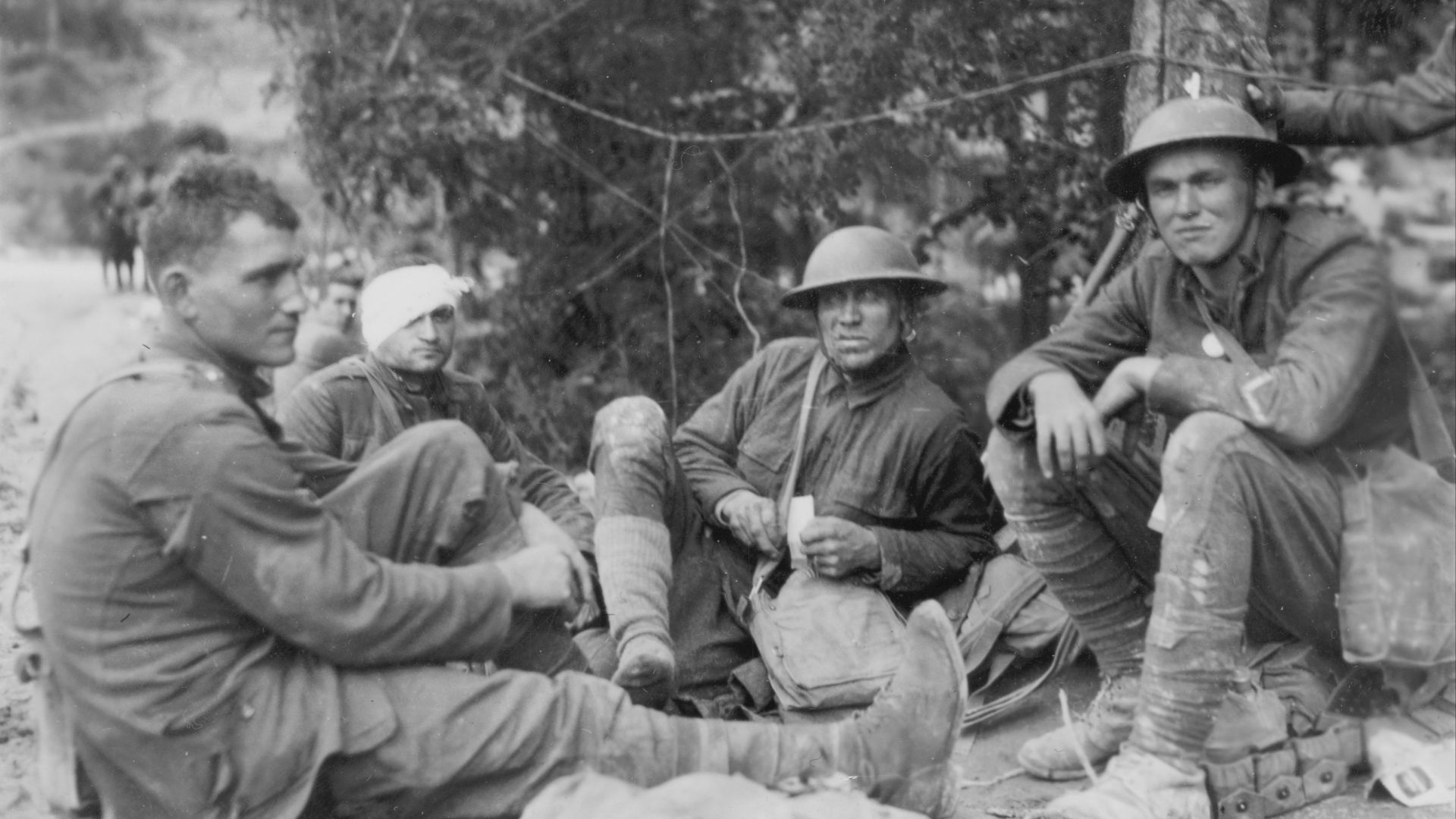 Allied soldiers, one with a bandaged head, sitting on the ground during World War I