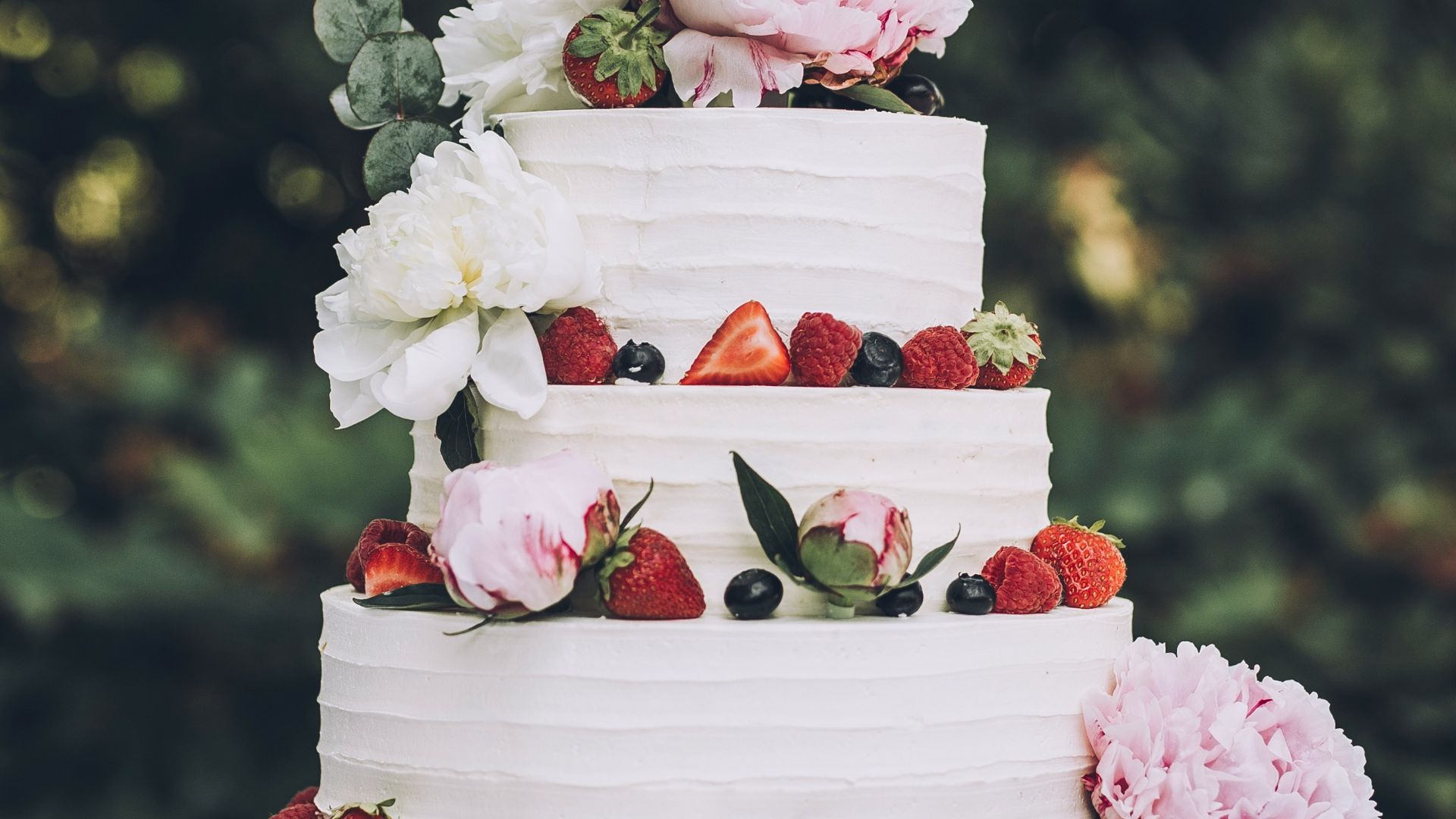 a white wedding cake with fresh strawberries and flowers