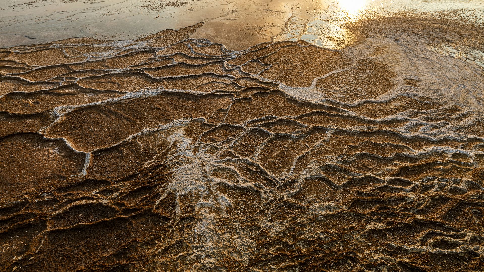 An aerial view of a desert with a sun in the background