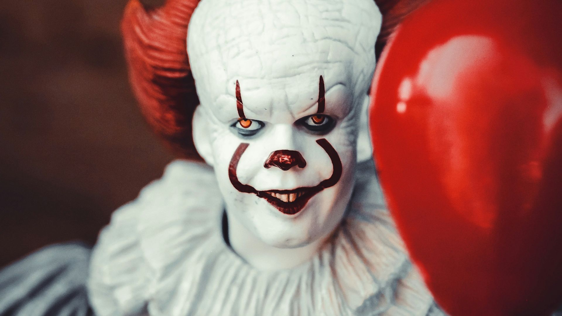 white and red clown holding heart balloon