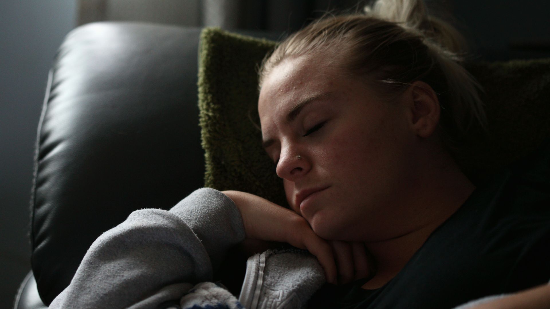 boy in gray hoodie lying on black leather couch