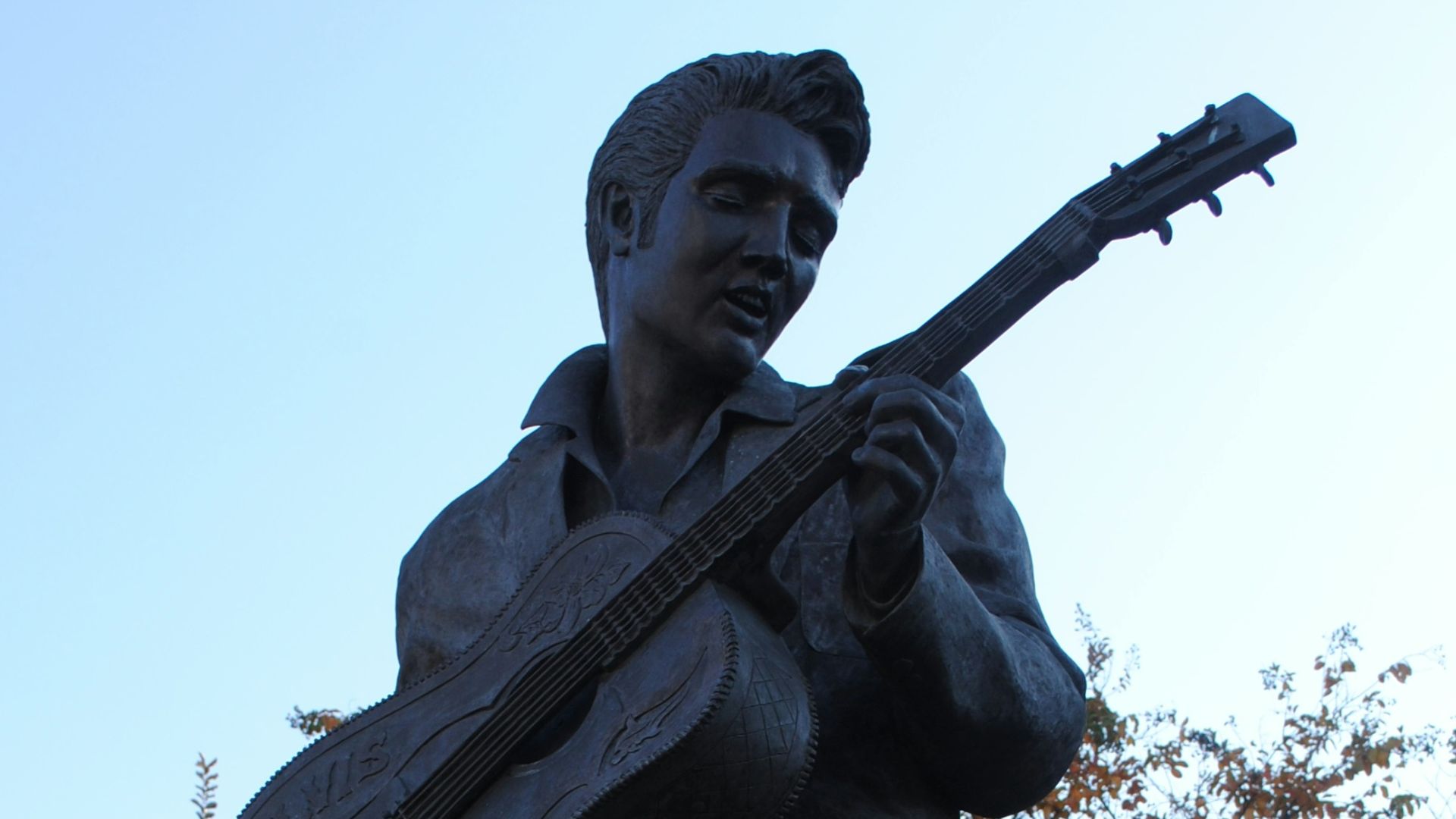 man holding stick statue under white sky during daytime