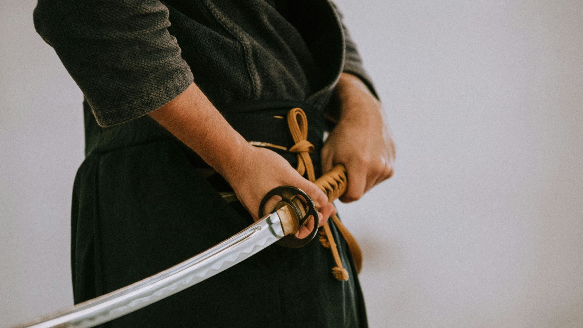 person in black long sleeve shirt and black skirt holding white leather belt