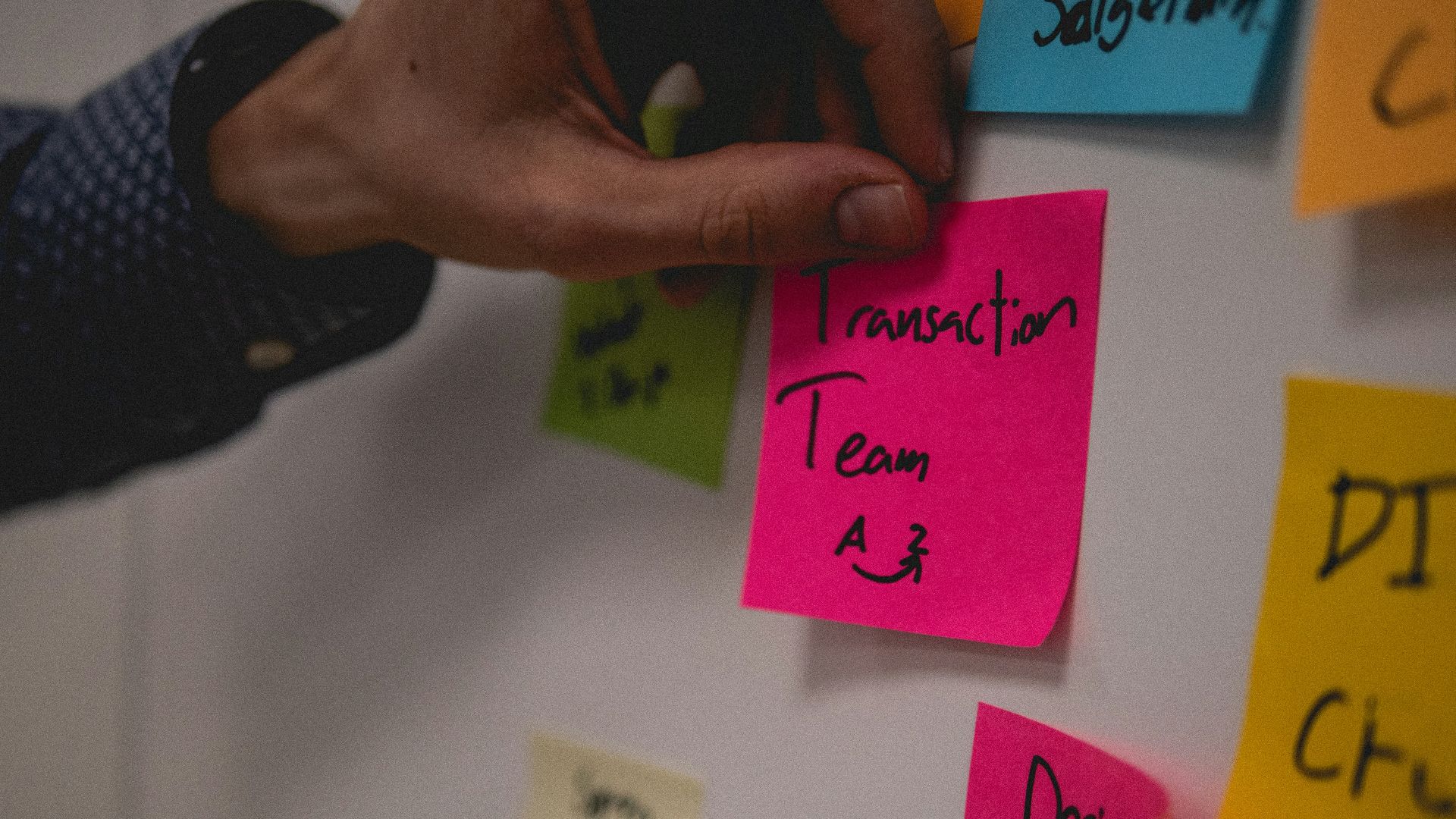 person holding pink sticky note