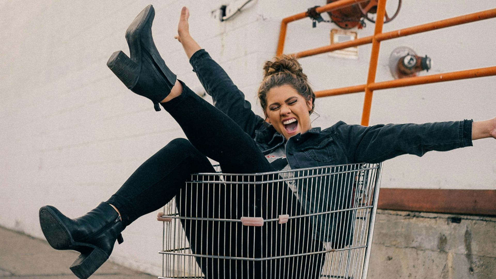 man in black jacket and black pants sitting on yellow metal fence