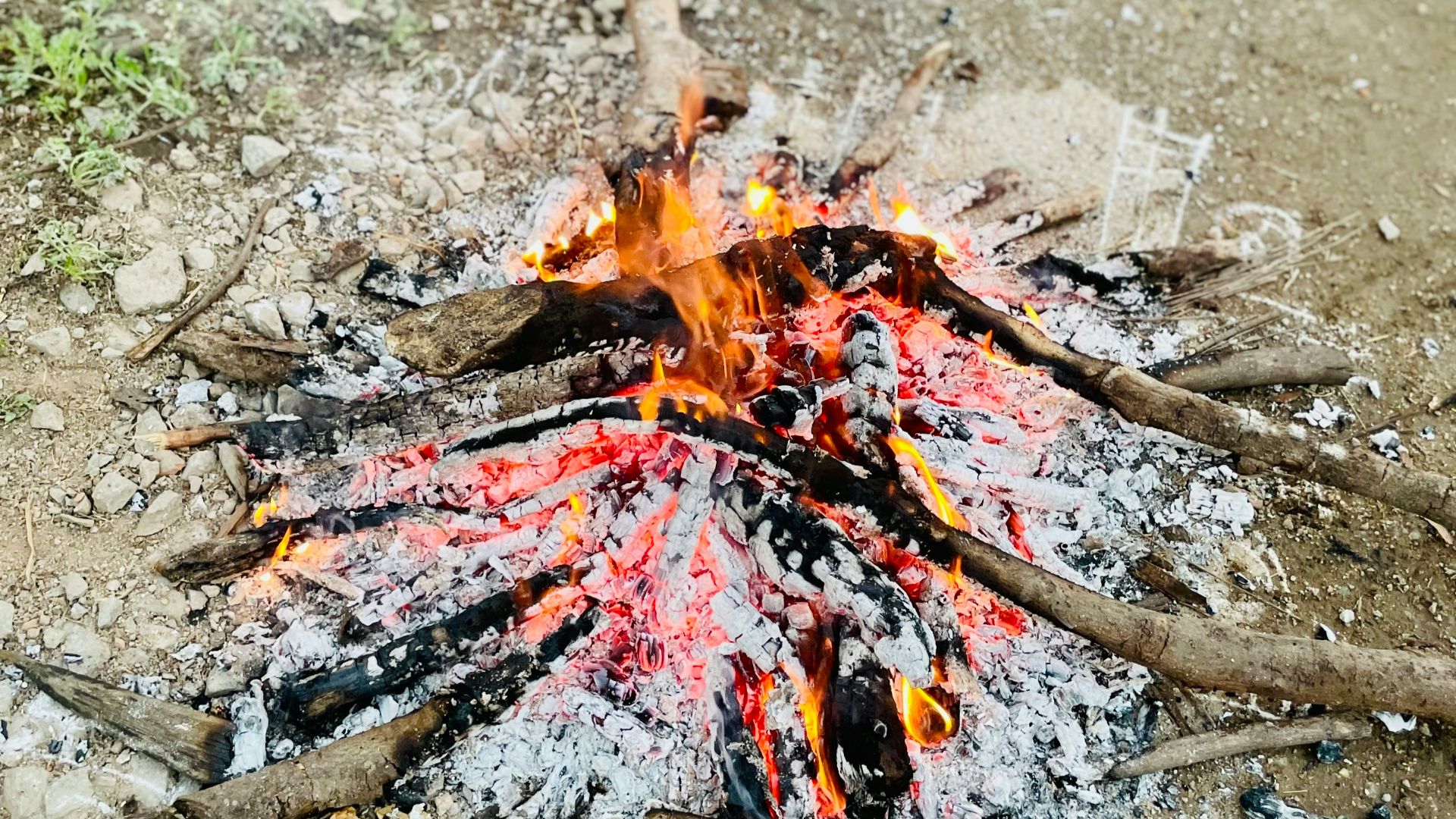 a campfire is burning in the middle of a dirt field