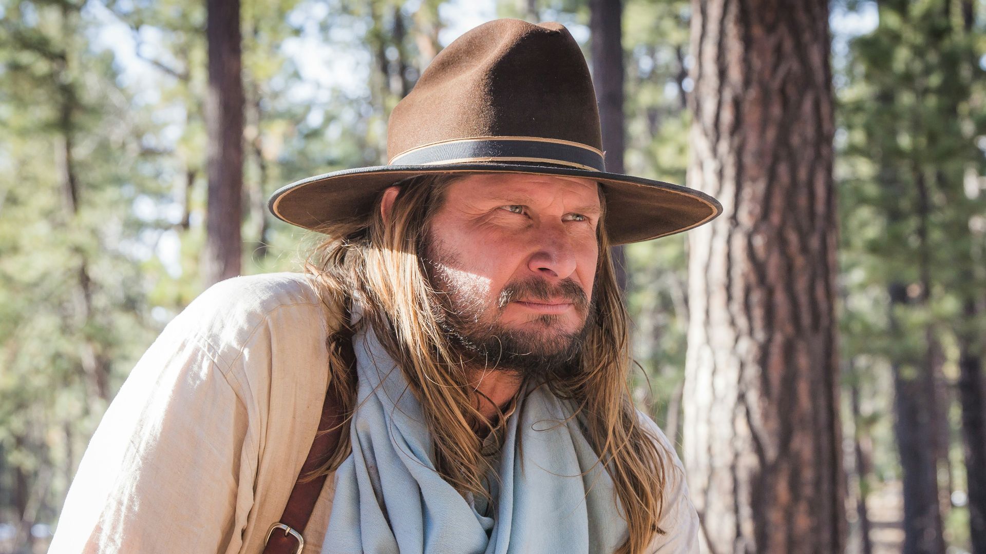 man wearing brown cowboy hat and gray scarf
