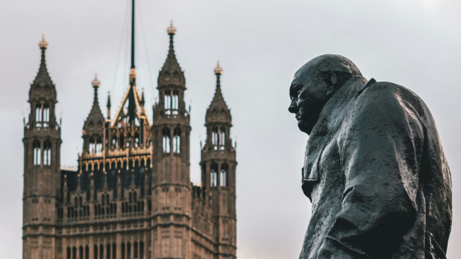 man wearing coat statue showing building with flag