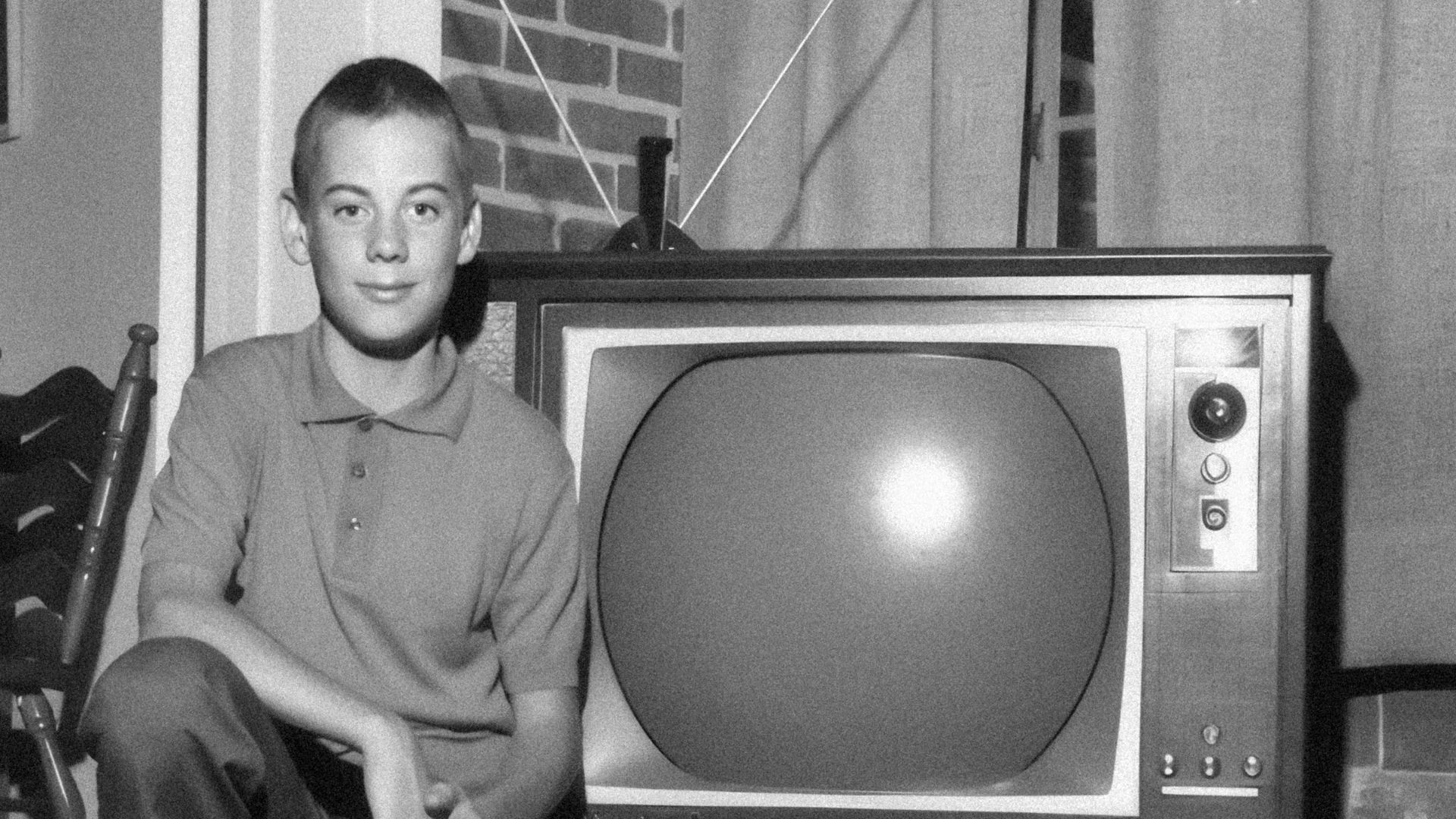 a young man sitting in front of a television