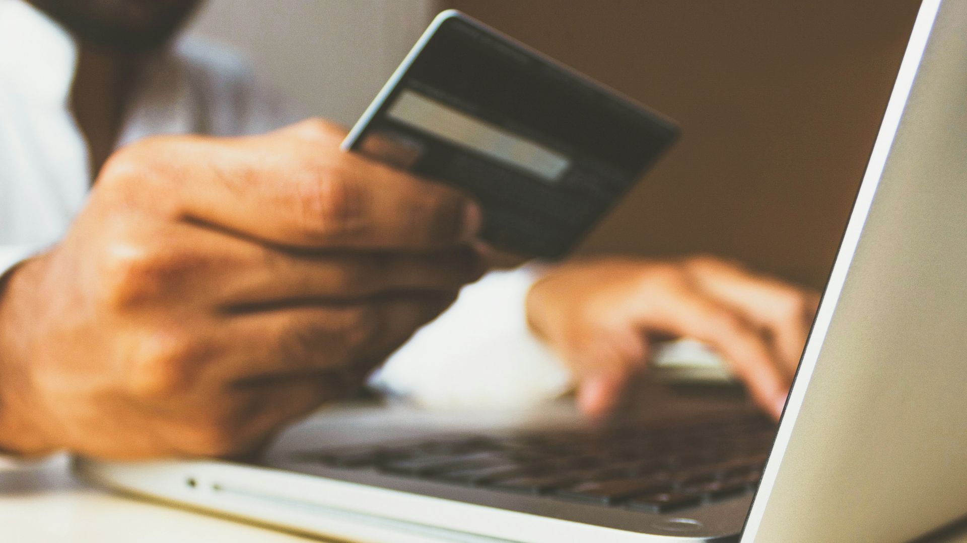 person using laptop computer holding card