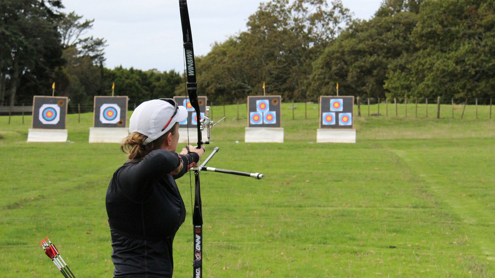 a woman is practicing archery in a field