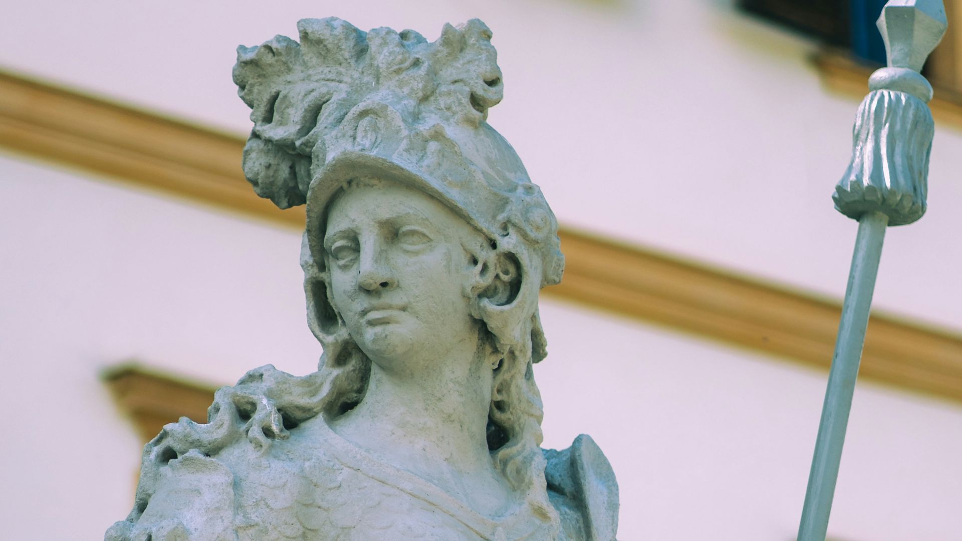 A statue of a man holding a spear in front of a building