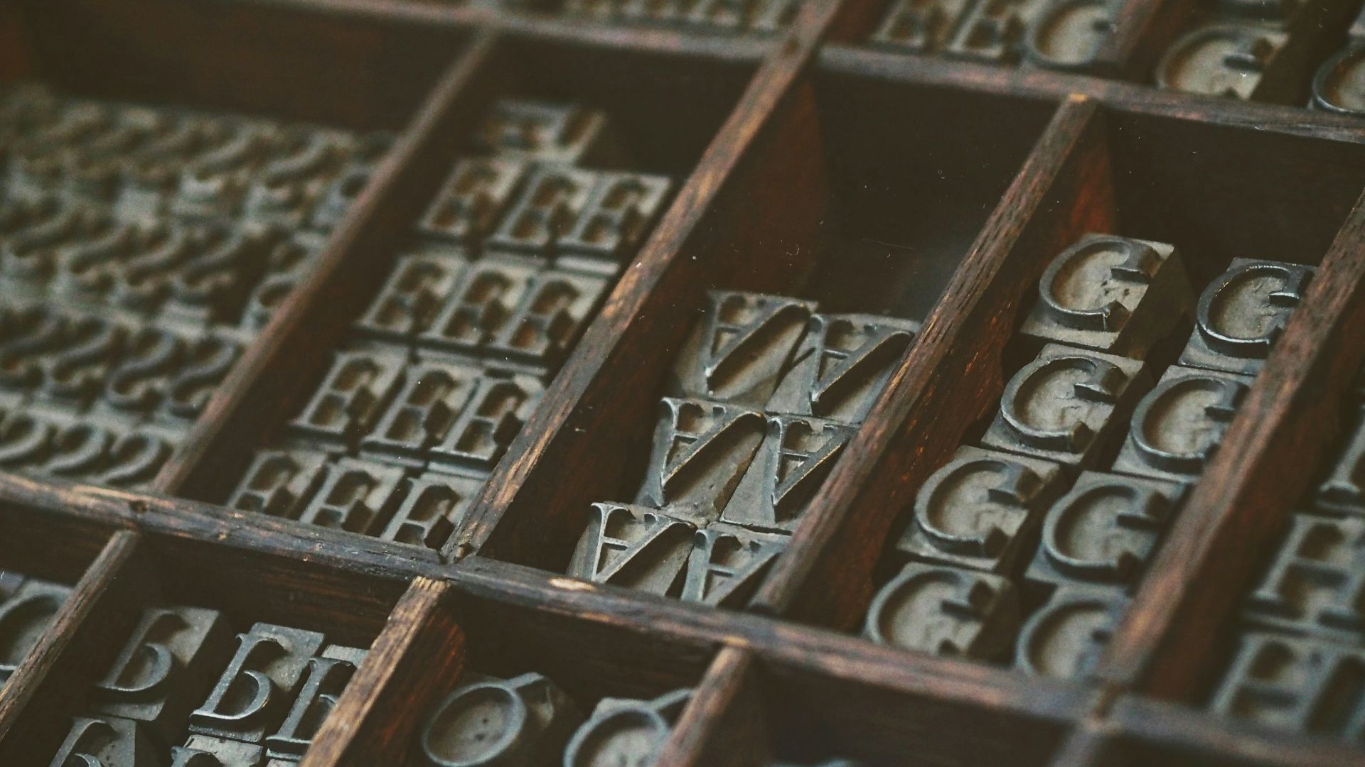 gray assorted-letter jewelries in brown wooden organizer boxes