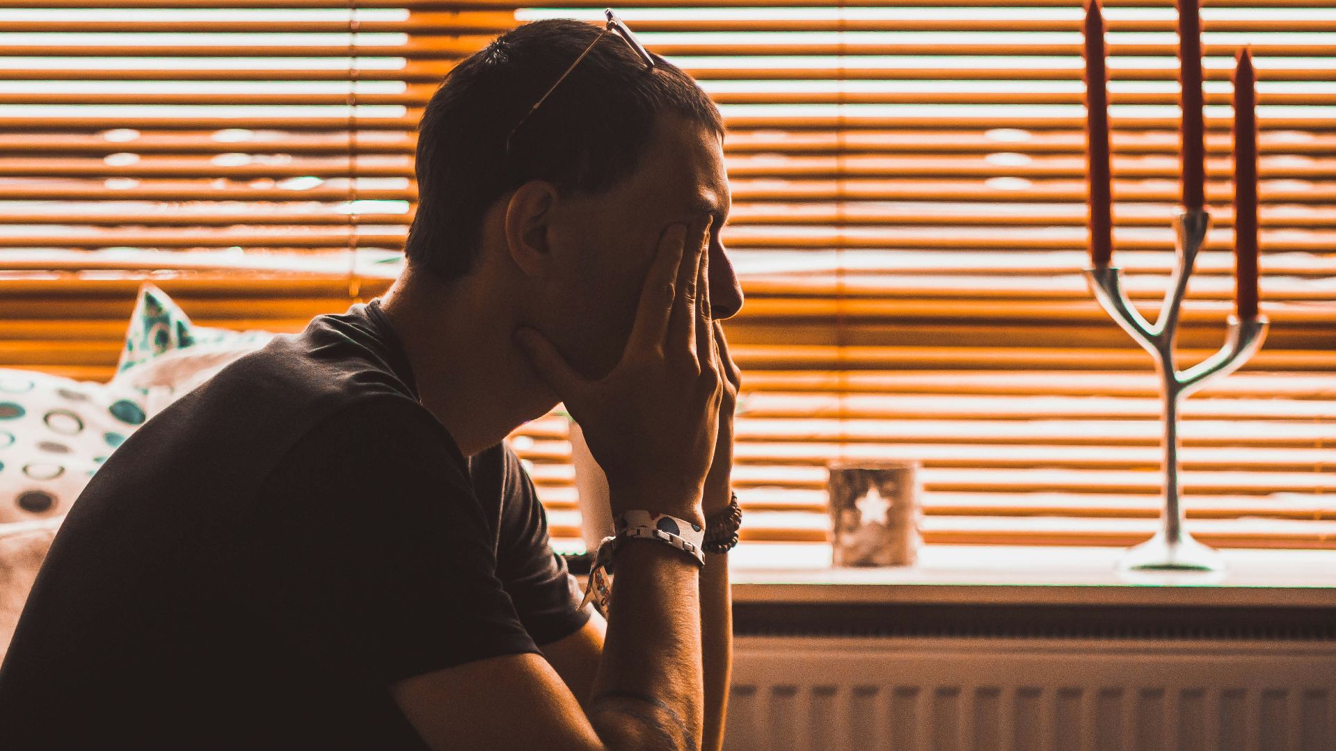 man sitting on chair covering his eyes