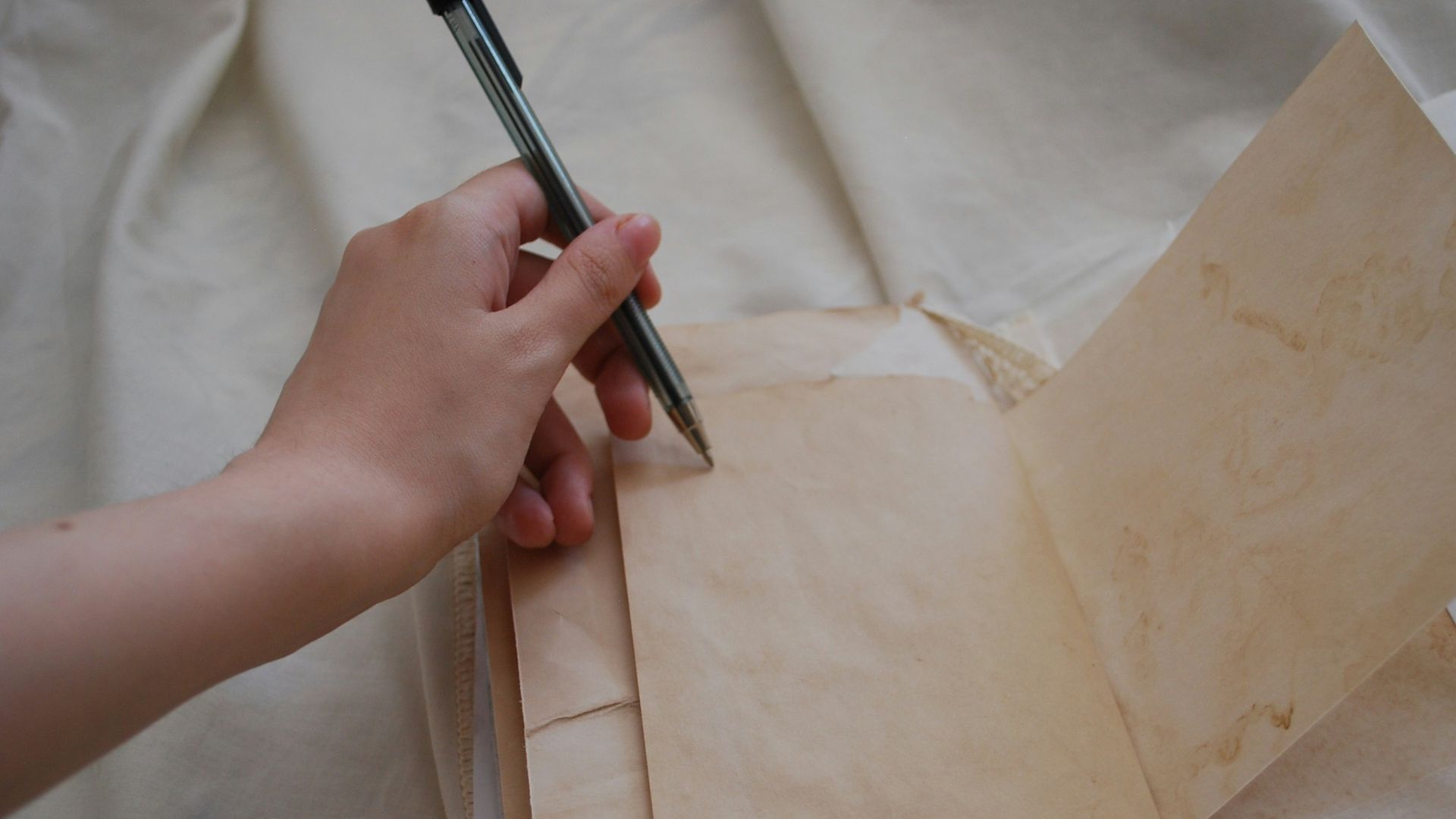 A person holding a pen and writing on a piece of paper