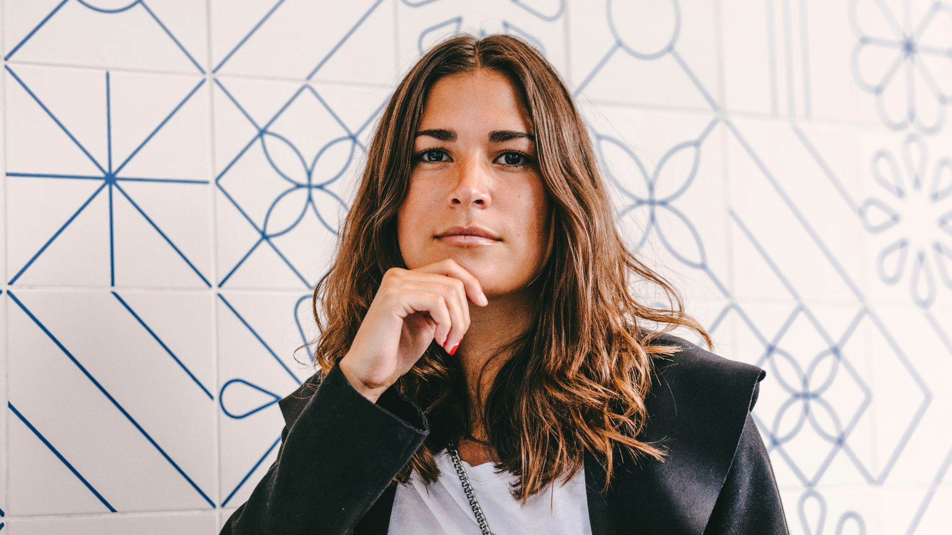 woman in black blazer covering her face with her hand
