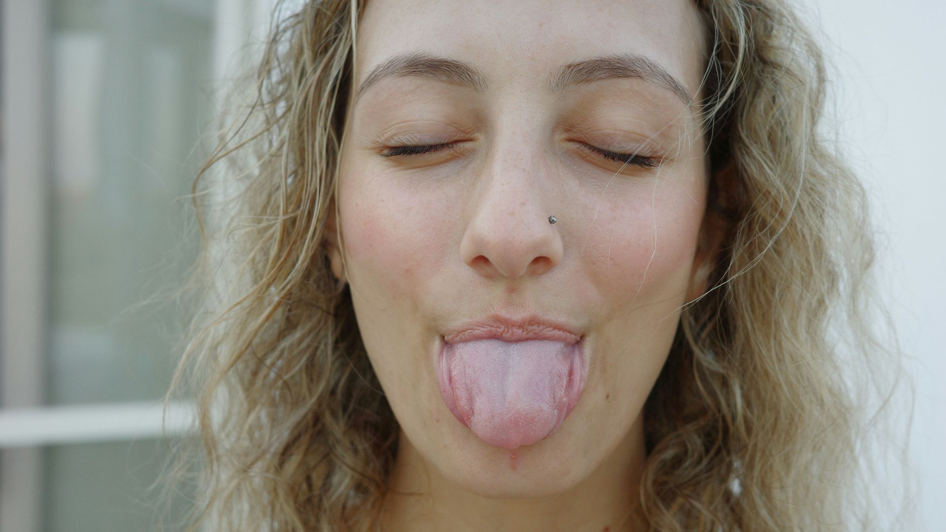 A woman sticking her tongue out with her eyes closed