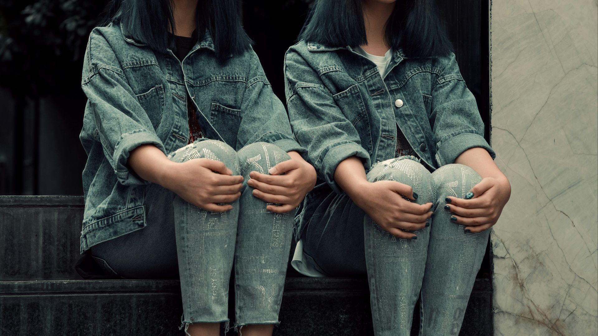 two young women sitting on the steps of a building