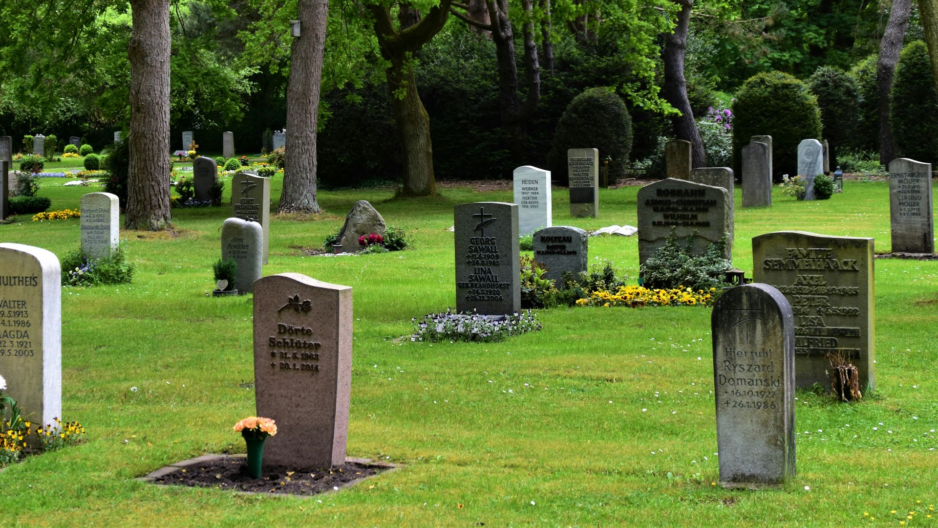 gray concrete cross on green grass field during daytime