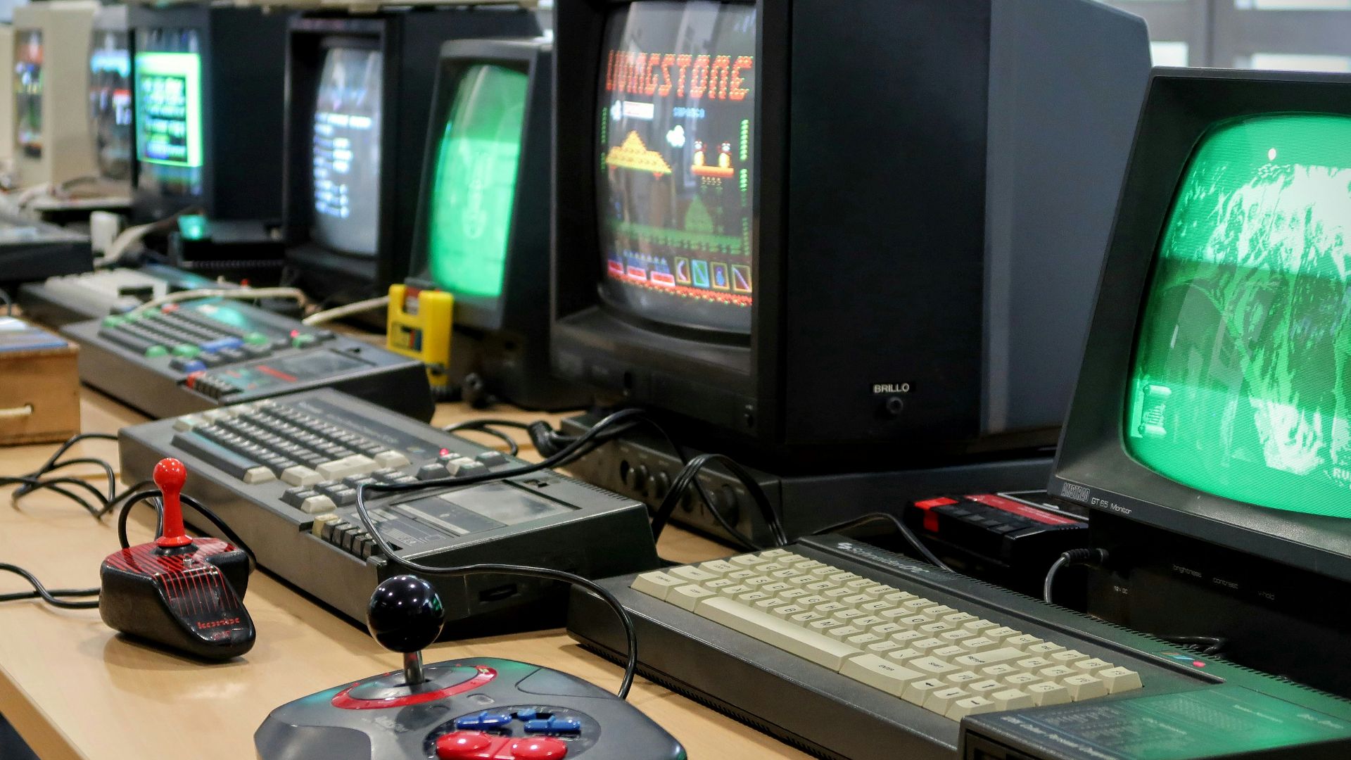a row of computer monitors sitting on top of a desk