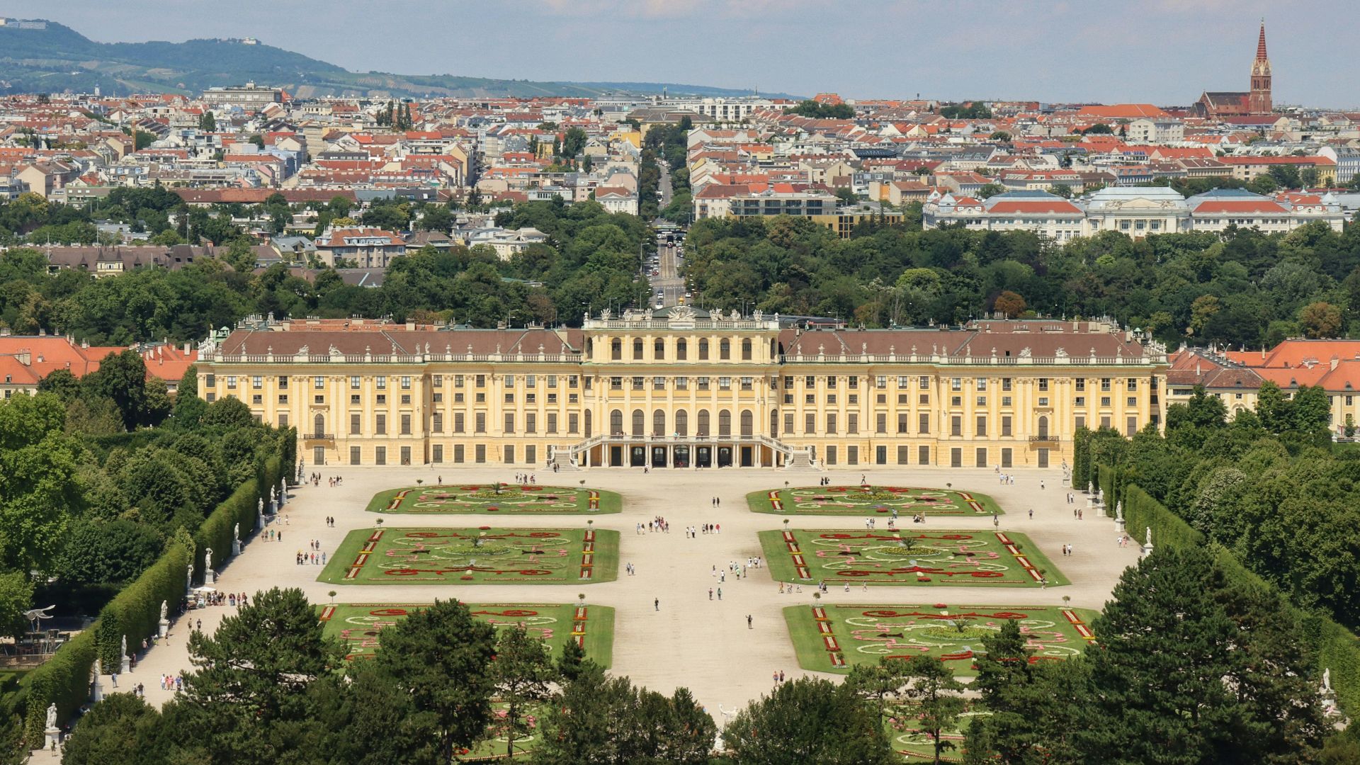 a large building with a courtyard and trees in front of it with Schönbrunn Palace in the background