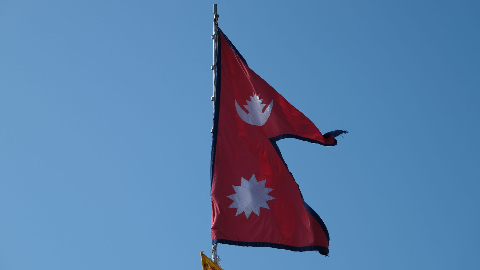 Two flags flying in the wind on a clear day
