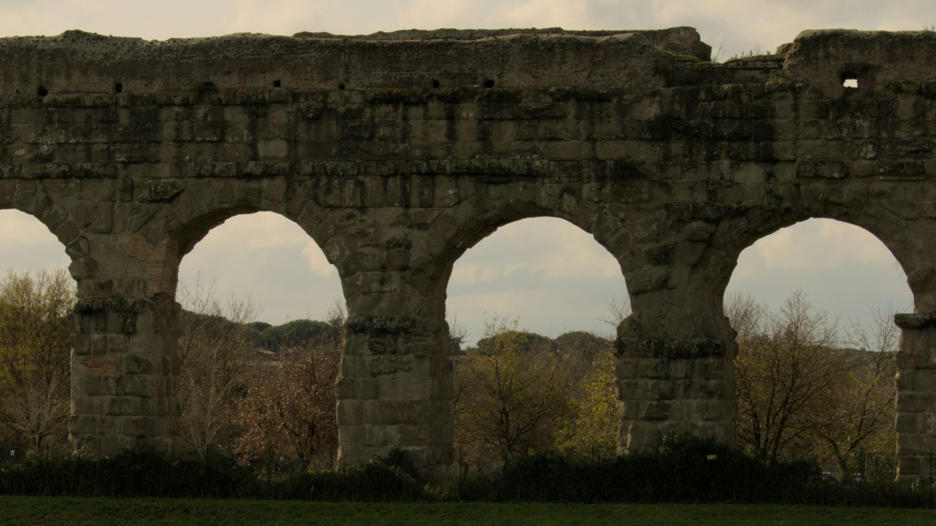 A man riding a horse in front of a stone wall