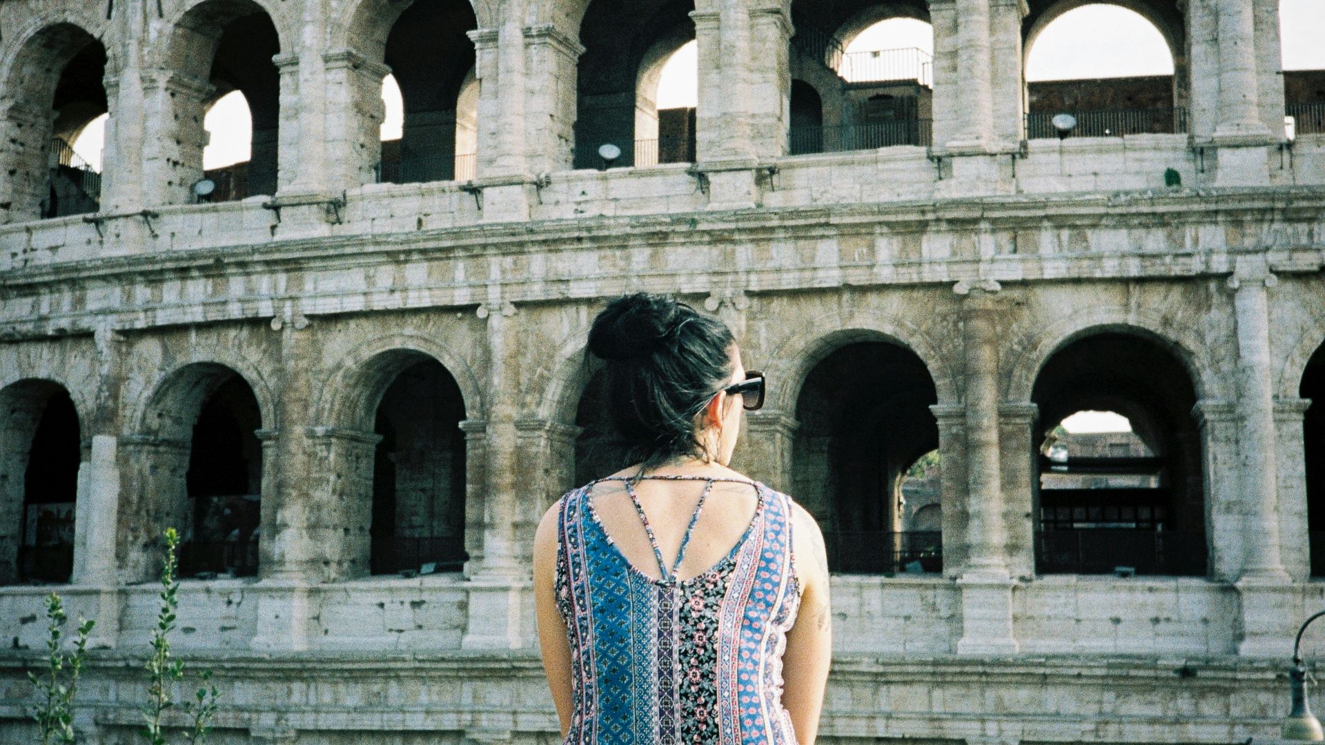 A woman sitting on a ledge in front of an ancient building