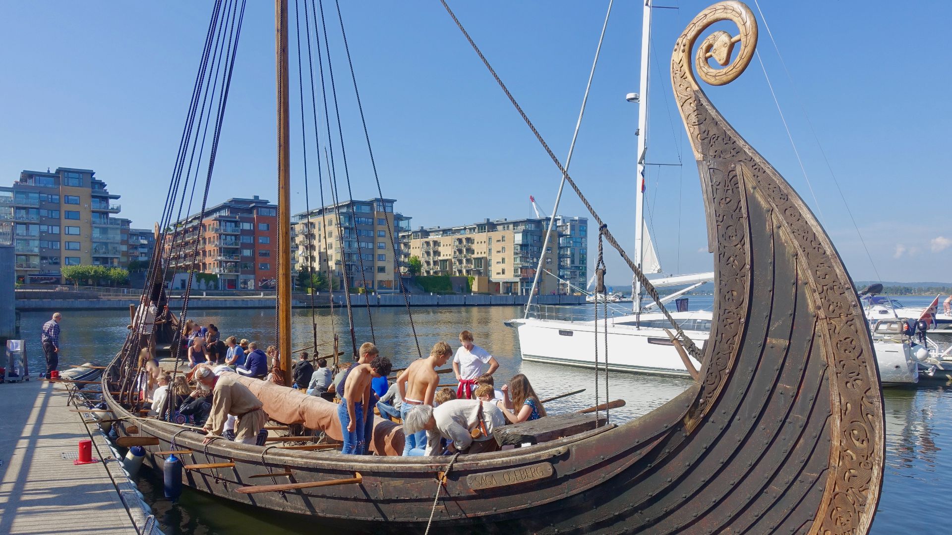 File:Saga Oseberg viking ship replica Tønsberg Norway Young students oars mooring Byfjorden Harbour havn Brygga pier board walk dock Fore Bow stempost Framstavn Kaldnes Apartements 2019-08-26 blurred faces 5172.jpg