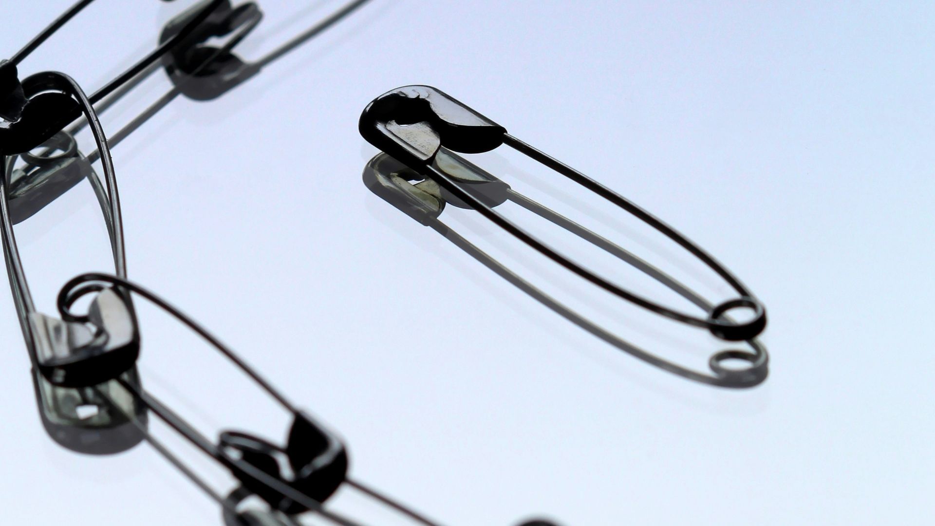 silver safety pin on white paper