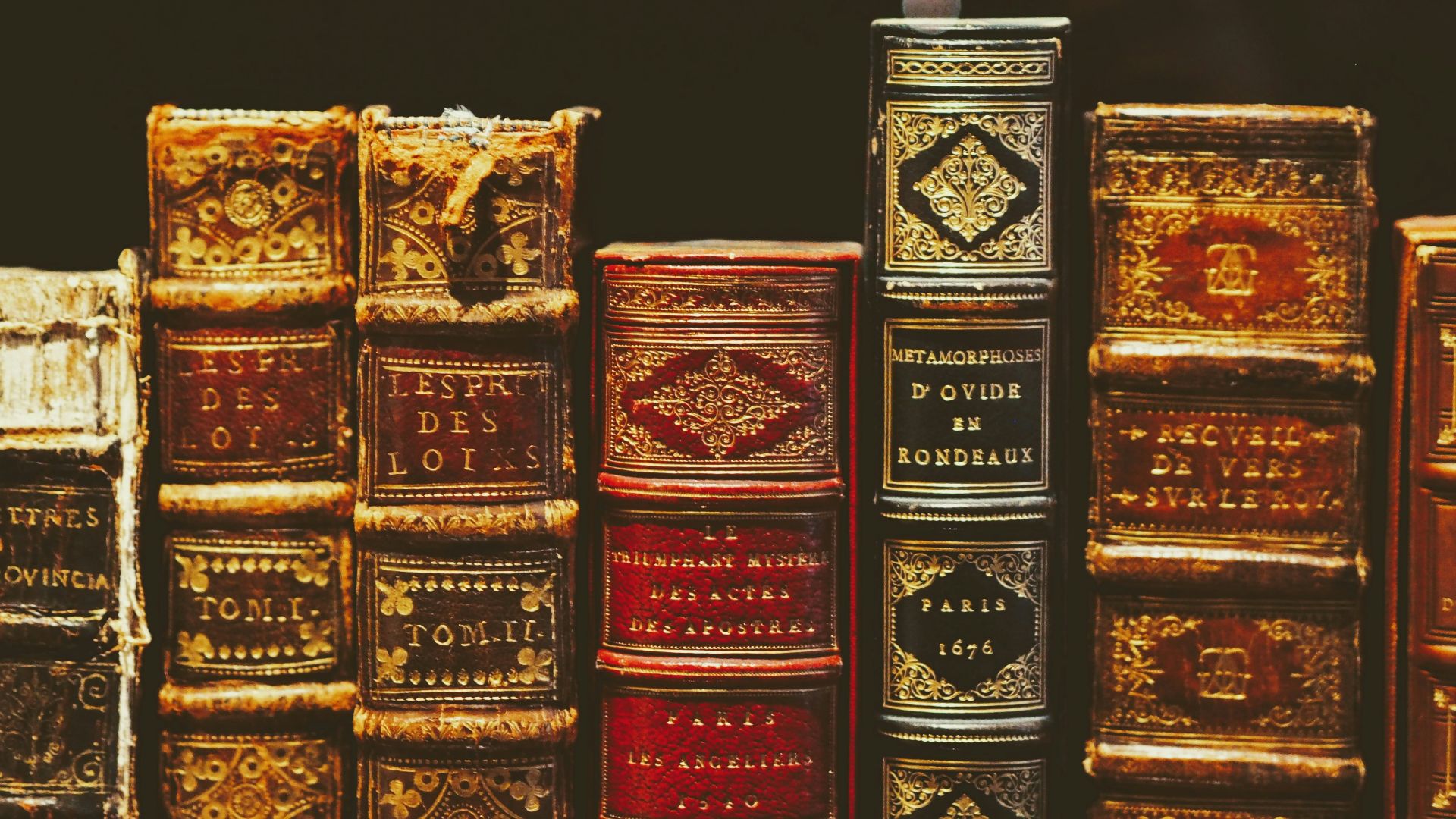 seven hardbound books on black surface