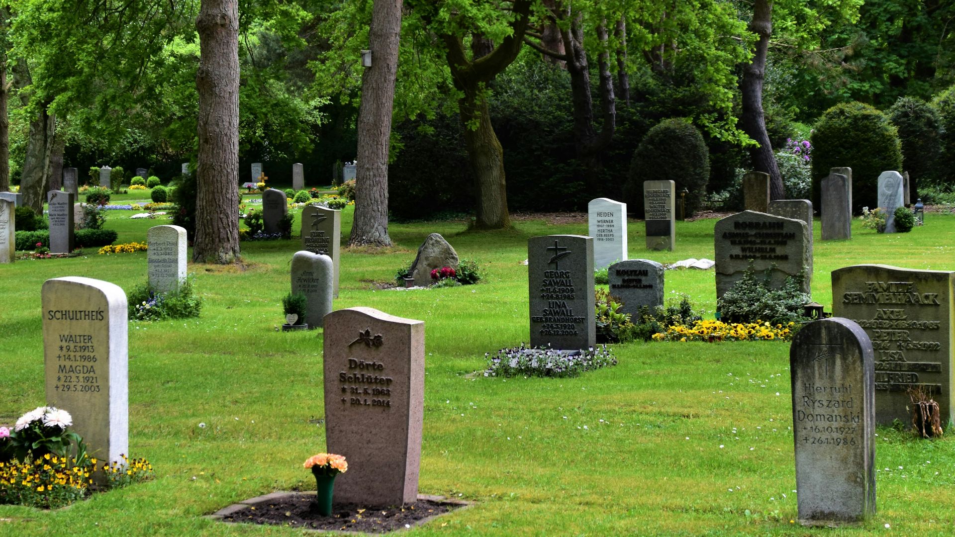 gray concrete cross on green grass field during daytime