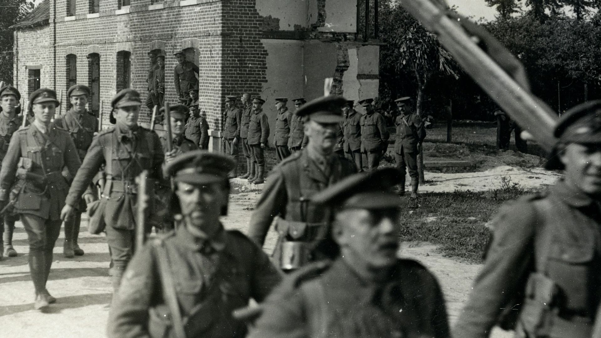 grayscale photography group of soldier walking outdoors