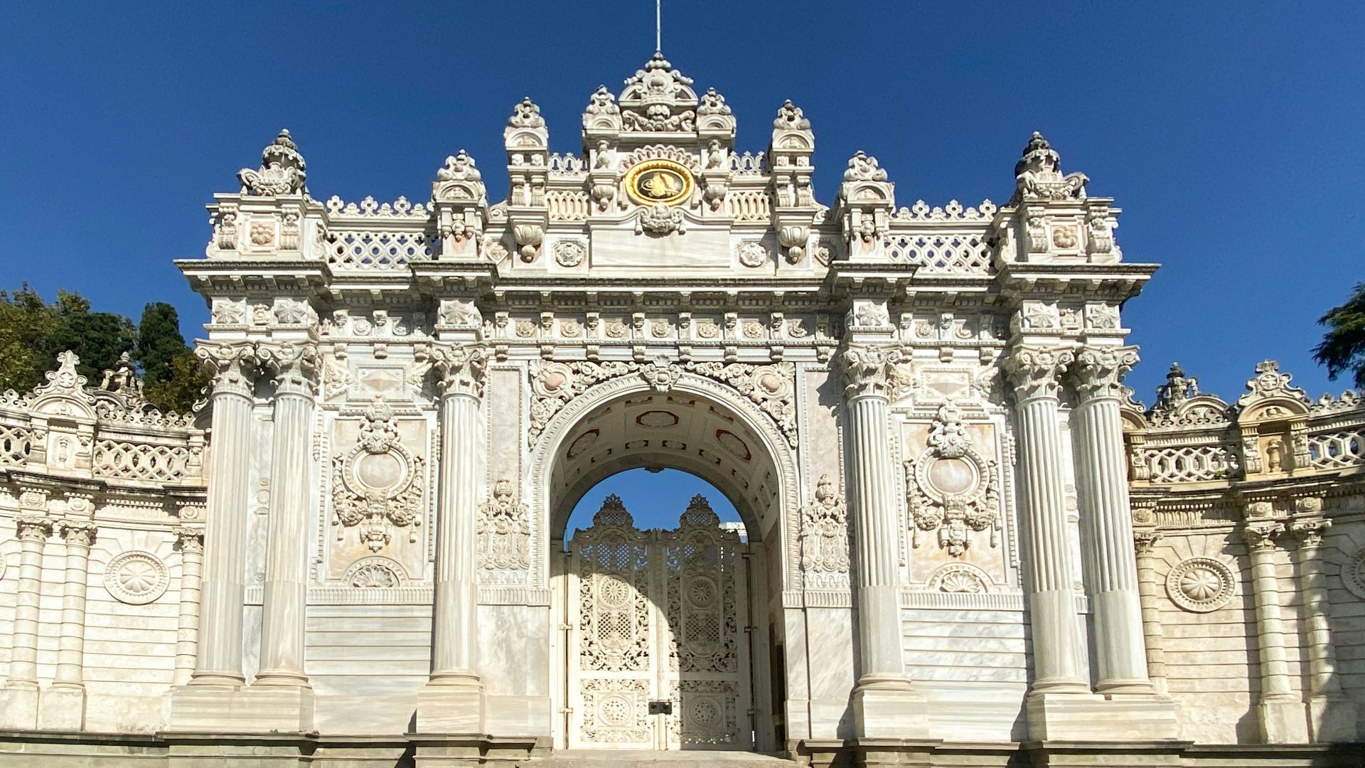 a large white building with a large arched doorway with Dolmabahçe Palace in the background