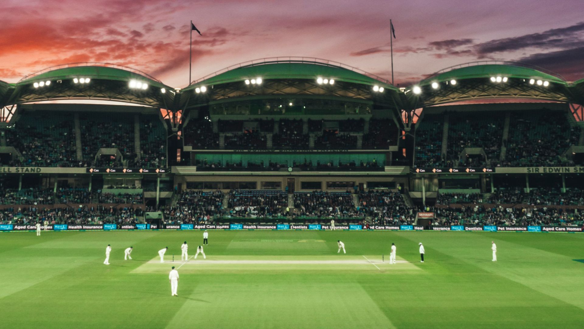 people watching game of cricket during sunset