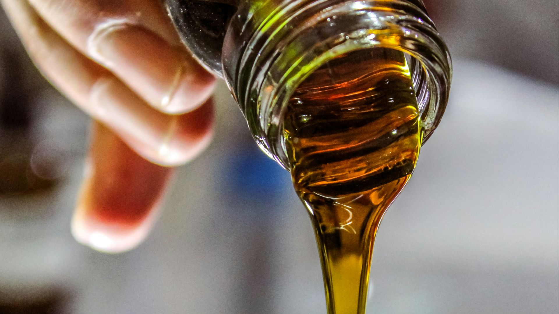 person holding clear drinking glass with brown liquid