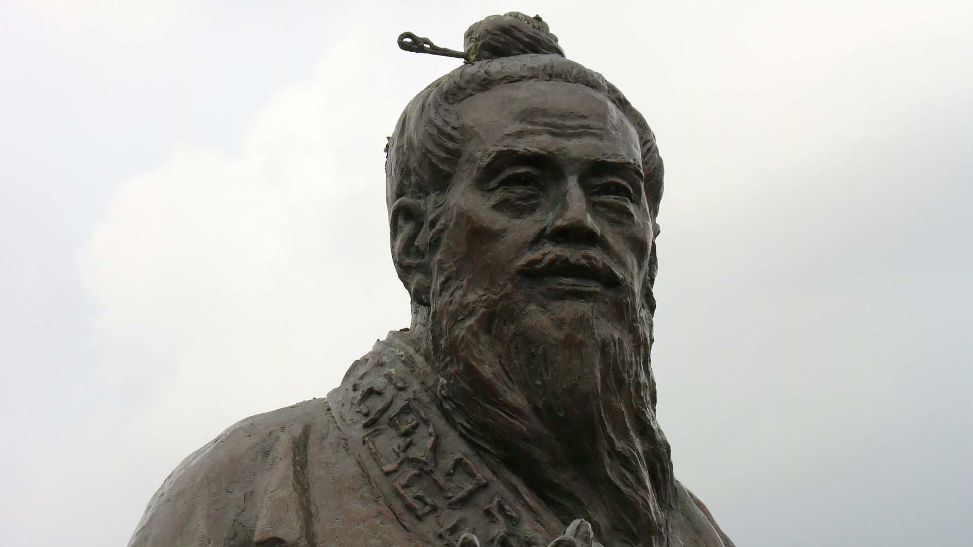 man in hat statue under white clouds during daytime