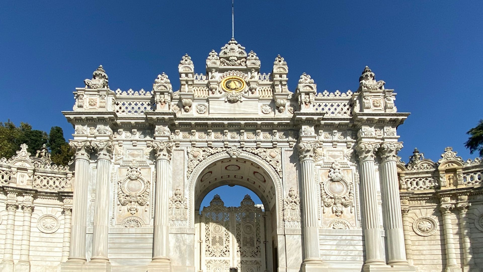 a large white building with a large arched doorway with Dolmabahçe Palace in the background