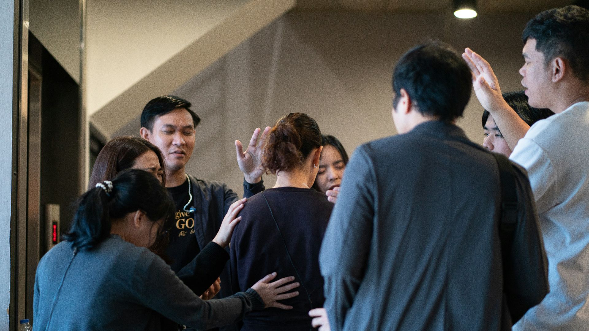 Group of people praying around a woman