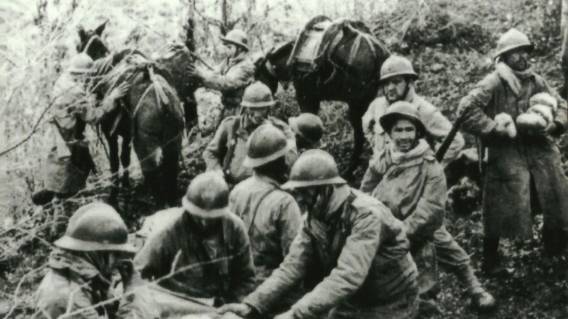 Soldiers in helmets carrying wounded comrade on stretcher